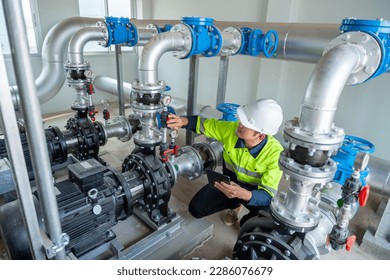 A worker at a water station is closing a water pipe valve in a large industrial estate. Water pipes. Industrial plumbing. - Powered by Shutterstock