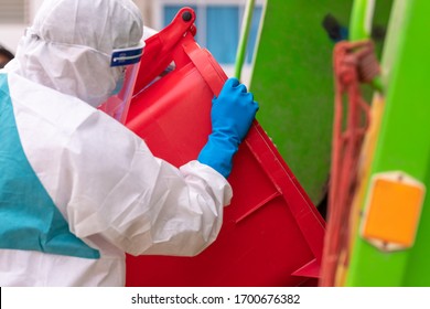 Worker Wear PPE Protective Clothing Against Corona Virus Of Infectious Waste Garbage Collector Truck Loading Waste And Trash Bin.