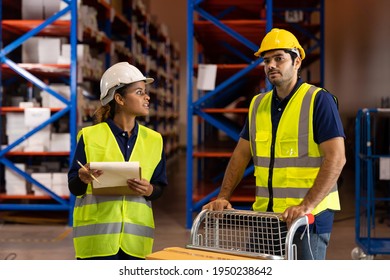 Worker wear safety helmet and holding clipboard and push cart in warehouse store. Group of male and female warehouse worker checking storage box parcel in factory warehouse. Inspection quality control