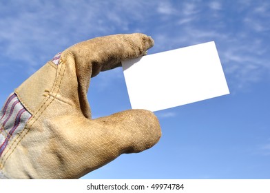 Worker Wearing Leather Work Glove Holding A Blank Business Card Against A Blue Sky