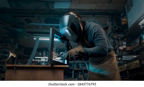 Worker Wearing A Mask And Gloves Soldering Metal Parts