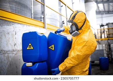 Worker wearing protection equipment and gas mask working in chemicals production factory disposing biohazard waste.
