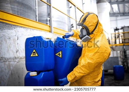 Worker wearing protection equipment and gas mask working in chemicals production factory disposing biohazard waste.