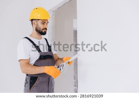 Worker wearing protective gloves using snips to cut a metal corner bead for plasterboard installation during home renovation