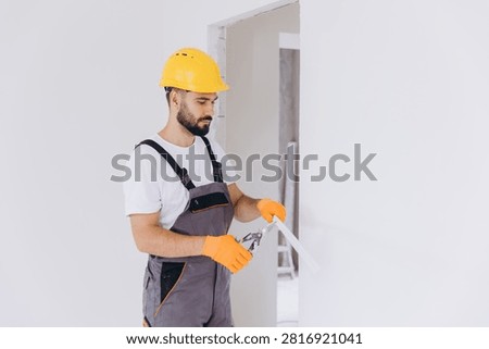 Worker wearing protective gloves using snips to cut a metal corner bead for plasterboard installation during home renovation