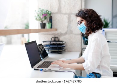 Worker Wearing Protective Mask In Safe Office. Protection Employees On Workplace At Hotel Reception. Young Woman Working As Receptionist. Social Distance During Covid Quarantine, Staff Safety.