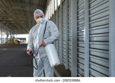 Worker Wearing Protective Suit Disinfection Gear Disinfect Surface Public Place Parking. Side View Of Disinfector Safety Overall And Respiratory Mask Covid Pandemic Disinfection Preventive Measures