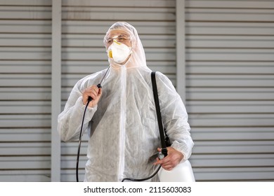 Worker Wearing Protective Suit Disinfection Gear Disinfect Surface Public Place Parking. Side View Of Disinfector Safety Overall And Respiratory Mask Covid Pandemic Disinfection Preventive Measures