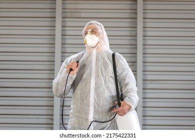 Worker Wearing Protective Suit Disinfection Gear Disinfect Surface Public Place Parking. Side View Of Disinfector Safety Overall And Respiratory Mask Covid Pandemic Disinfection Preventive Measures