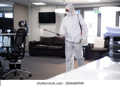 Worker wearing protective suit, face mask and gloves sanitizing office using an anti bacterial disinfectant spray. Hygiene in workplace during Coronavirus Covid 19 pandemic. - Powered by Shutterstock