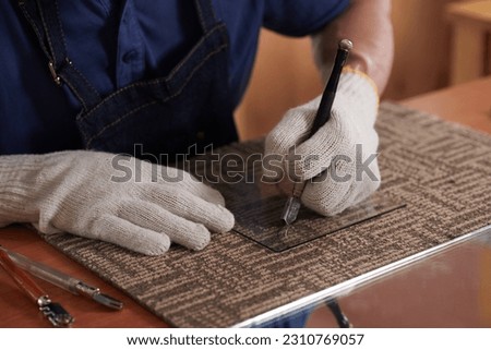 Worker wearing textile glasses when cutting piece of glass with glass cutter