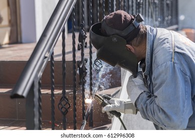 A worker welding metal handrails on the stairs. Wrought iron railings. Private house. Ukraine.