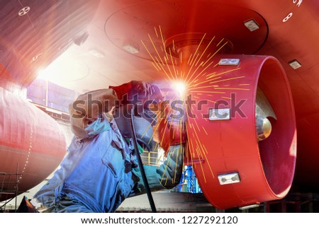 Worker Welding process with Metal steel hull and Proppeler Maintenance, wear equipment protective for safety, a large cargo ship repair in dry dock. shipyard Thailand 