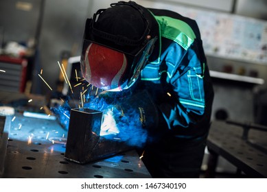 Worker welding two pieces of square tube to form a 90 degree angle