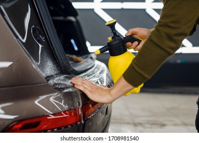 Worker Wets Rear Bumper Surface Of Car, Detailing