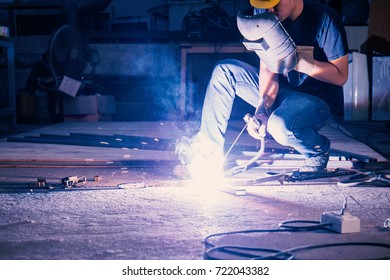 Worker while doing a welding with arc welder with the smoke, asian man with his hands welding in heavy industry - Powered by Shutterstock