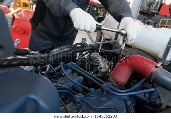 A worker\
in white gloves tightens a bolt or nut with a socket wrench. Plant\
for the production of machinery or car service. Repair of engines\
of tractors and cars. Industrial\
zone.