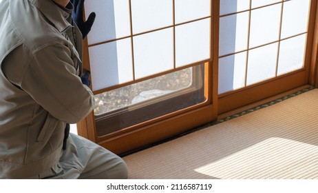 A worker who adjusts the shoji screen.Japanese-style paper sliding doors.Shoji with glass window behind a sliding bottom half.