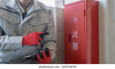A worker who inspects a fire extinguisher. The word 