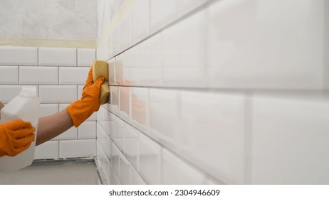 A worker wipes ceramic tiles with a sponge after work. The tiler wipes the tiles after laying, professional highly qualified technology for laying and finishing tiles. 