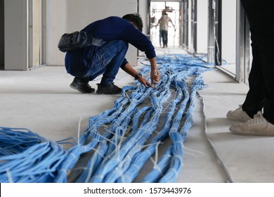Worker wiring LAN cable at construction site. Unfinished Installation network system. - Shutterstock ID 1573443976