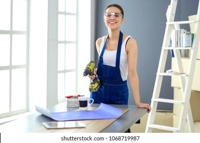 Worker Woman With Drill Standing In New Home