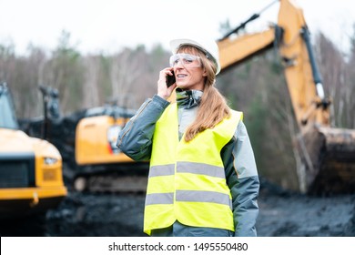 Worker woman in open-cast mining using phone talking to manager