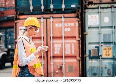 Worker Woman In Safety Jumpsuit Workwear With Yellow Hardhat And Use Smartphone Check Container At Cargo Shipping Warehouse. Transportation Import,export Logistic Industrial Service