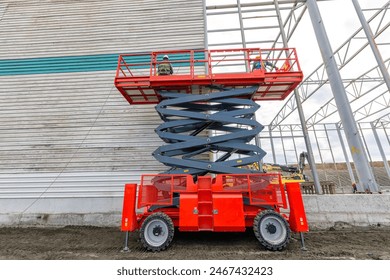 Worker is working for exterior cladding of factory on the scissor manlift in the construction side.