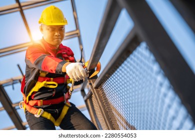 A worker working at height equipment. Fall arrestor device for worker with hooks for safety body harness on the roof structure. Safety body construction. selective focus of hook safety body harness. 