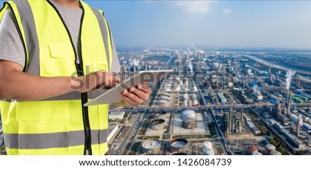 worker working on pad with oil and gas refinery background