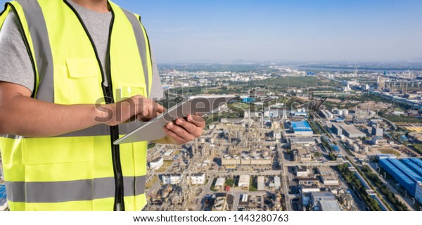 worker working on pad with oil and gas refinery\
background,Smart factory