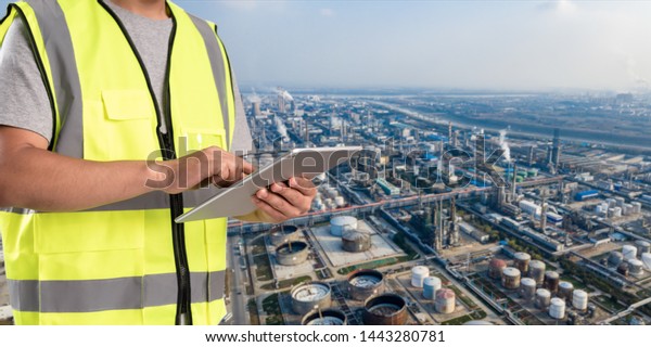 worker working on pad with oil and gas refinery\
background,Smart factory