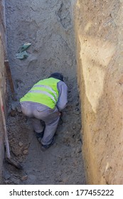 Worker Working In Trench. No Ladder, No Hardhat, Not Working In The Trench Box. Dangers Of Trench Collapse. 