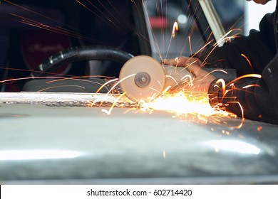 Worker Works With Angle Grinder In A Car Repair Shop