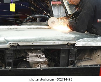 Worker Works With Angle Grinder In A Car Repair Shop