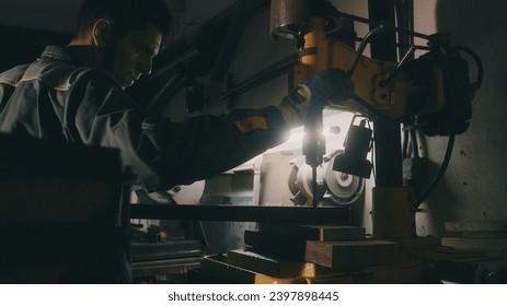 A worker works on a metal drilling machine in a workshop. Metallurgy production. A machinist operating a traditional non-CNC milling machine in a machine shop. Operates an industrial machine - Powered by Shutterstock