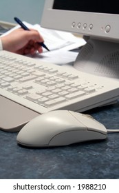 Worker writes while working at computer