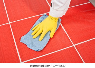 Worker With Yellow Gloves And Blue Towel Clean Red Tiles Grout From Cement Milk After Grouting
