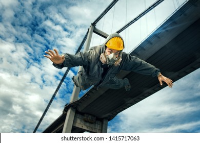 worker with yellow hard hat falling down on city background 