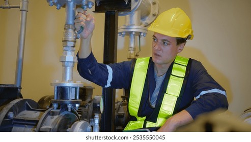 A worker in a yellow helmet and vest adjusts a pipe valve in an industrial setting, highlighting maintenance and safety within engineering environments, showcasing modern engineering practices. - Powered by Shutterstock