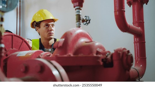 A worker in a yellow helmet and vest adjusts a pipe valve in an industrial setting, highlighting maintenance and safety within engineering environments, showcasing modern engineering practices. - Powered by Shutterstock