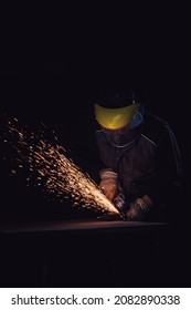 Worker With Yellow Mask Cutting A Metal Plate With A Circular Saw In A Factory With Yellow Sparks