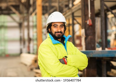 Worker young man with helmet and beard standing in a warehouse