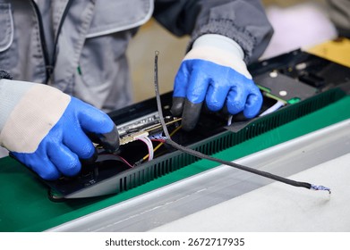 Workers assemble PCB into plastic housing for electronics manufacturing in a factory