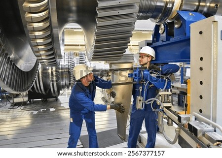 workers assembling and constructing gas turbines in a modern industrial factory