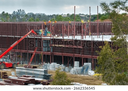 Workers assembling metal frame building at industrial construction site. Housing development in America. Real estate market in the USA