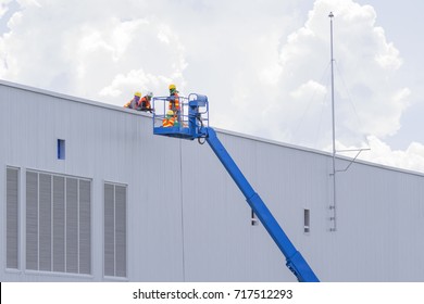 Workers in a baskets are installing sheet, building a factory.