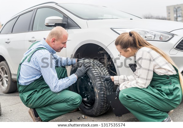 Workers at car\
service station examining tyre\
