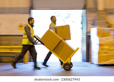 Workers carting boxes in warehouse - Powered by Shutterstock